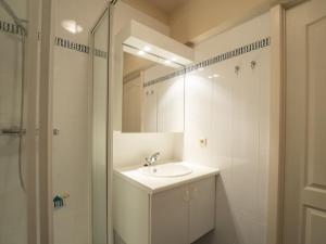 ein weißes Badezimmer mit einem Waschbecken und einem Spiegel in der Unterkunft Apartment Green Garden-8 by Interhome in De Haan