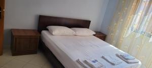 a small bedroom with a bed with a wooden headboard at Charming Apartment Lushnje in Lushnjë