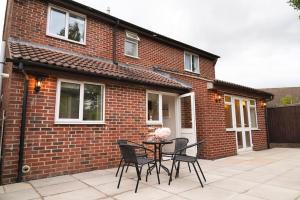 a patio with a table and chairs in front of a brick house at Tranquil Retreat in Bicester in Bucknell