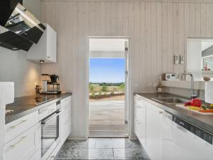 une cuisine avec des placards blancs et une vue sur l'océan. dans l'établissement Holiday Home Liesel - 700m from the sea in Djursland and Mols by Interhome, à Ebeltoft