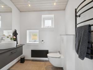 La salle de bains blanche est pourvue de toilettes et d'un lavabo. dans l'établissement Holiday Home Liesel - 700m from the sea in Djursland and Mols by Interhome, à Ebeltoft