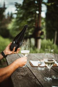 eine Person, die eine Flasche Wein auf einem Tisch mit zwei Gläsern hält in der Unterkunft Ottmanngut Suite and Breakfast in Meran
