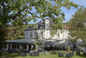 ein großes weißes Haus mit Stühlen im Hof in der Unterkunft Logis La Résidence in Le Val-dʼAjol