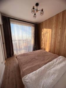 sypialnia z łóżkiem i dużym oknem w obiekcie Alma house - White w mieście Ałma-Ata