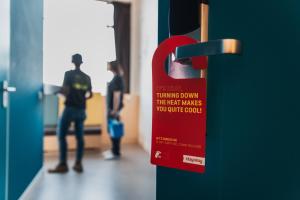 a red sign on a door with people standing in a hallway at Stayokay Hostel Heemskerk - fully renovated April 2026 in Heemskerk