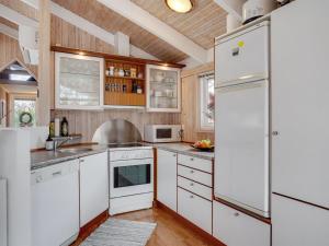 uma cozinha com armários brancos e um frigorífico branco em Holiday Home Alvy - 200m from the sea in Djursland and Mols by Interhome em Ebeltoft