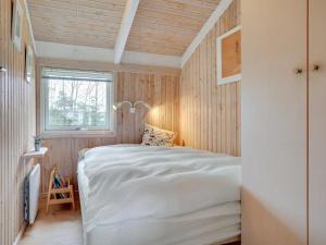 um quarto com uma cama branca num quarto com paredes de madeira em Holiday Home Alvy - 200m from the sea in Djursland and Mols by Interhome em Ebeltoft