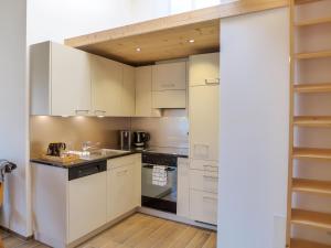 uma cozinha com armários brancos e electrodomésticos pretos em Apartment beim Ahorn by Interhome em Kandersteg