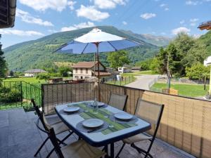 - une table bleue avec des chaises et un parasol sur le balcon dans l'établissement Holiday Home Ca' Virc by Interhome, à Olivone
