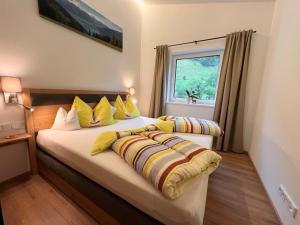 1 dormitorio con 2 camas con almohadas amarillas y ventana en Apartment Apartement Haus Dankl by Interhome, en Fusch an der Glocknerstrasse