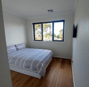 een witte slaapkamer met een bed en een raam bij Maruve Guesthouse 12 min from Melb airport in Melbourne