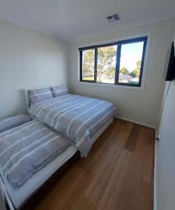 1 dormitorio con cama y ventana en Maruve Guesthouse 12 min from Melb airport, en Melbourne