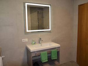 ein Bad mit einem Waschbecken, einem Spiegel und grünen Handtüchern in der Unterkunft Apartment Apart Hof Achenrainer by Interhome in Landeck
