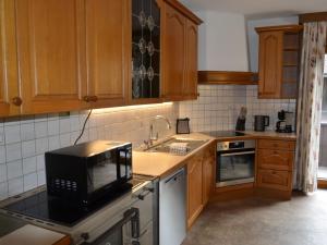 a kitchen with wooden cabinets and a black microwave at Apartment Apart Hof Achenrainer by Interhome in Landeck