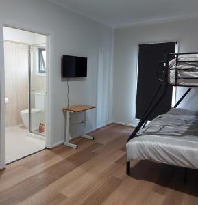 a bedroom with a bed and a desk and a television at Maruve Guesthouse 12 min from Melb airport in Melbourne