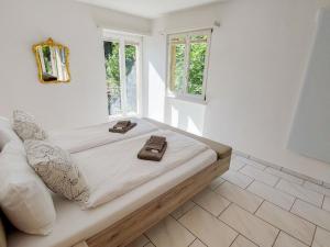 ein weißes Zimmer mit einem Bett mit zwei braunen Schuhen darauf in der Unterkunft Apartment Mulino Vecchio by Interhome in Ronco sopra Ascona
