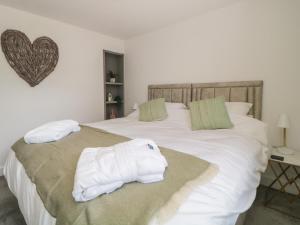 Un dormitorio con una cama con toallas blancas. en Secret Lookout, en Calstock