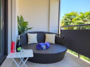 a wicker chair with hats and a table on a balcony at Apartment App- Julia Caslano by Interhome in Caslano