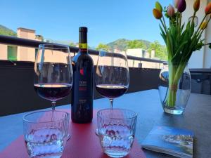 Dois copos de vinho numa mesa com uma garrafa de vinho em Apartment App- Julia Caslano by Interhome em Caslano