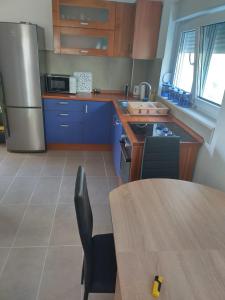 a kitchen with blue cabinets and a table and a refrigerator at Apartments Miličević in Gradac