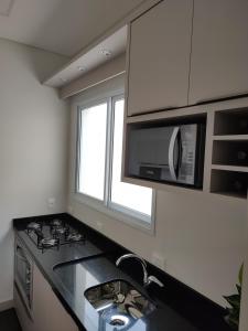 a kitchen with a sink and a microwave at Praia de Palmas - Lindo Apartamento in Governador Celso Ramos