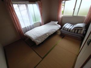 Habitación con cama, silla y ventanas. en メゾンドヴィラ, en Kami-furano