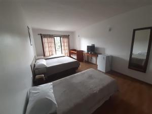 a hotel room with two beds and a mirror at HOTEL CAMPO ALEGRE in Campo Alegre