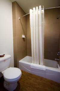 a bathroom with a toilet and a bath tub with a shower curtain at West Coast Inn Santa Ana in Santa Ana