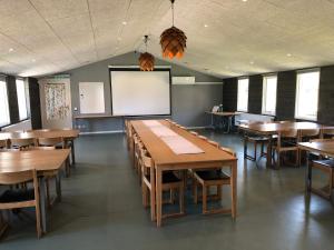 uma sala de aula com mesas de madeira e um ecrã branco em Marsbäcken em Västervik