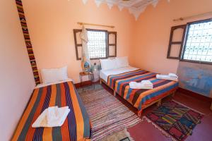 a room with two beds and two windows at La Kasbah du Jardin in Aït Benhaddou