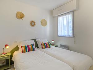 twee bedden in een witte kamer met een raam bij Apartment Les Eiders by Interhome in Carnac