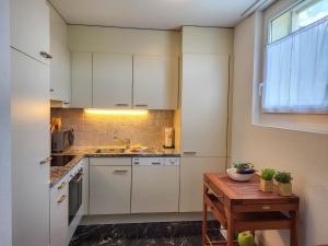 une cuisine avec des placards blancs et une table en bois dans l'établissement Apartment Torre Tessuti 3-2 by Interhome, à Locarno