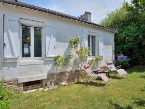 a house with two chairs and a table in the yard at Holiday Home L'escapade by Interhome in Auray
