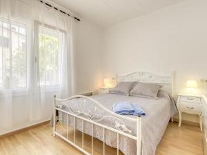 een wit bed in een witte slaapkamer met een raam bij Holiday Home Luna by Interhome in Empuriabrava