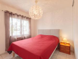 1 dormitorio con cama roja y lámpara de araña en Holiday Home Les Sables by Interhome en Royan