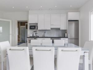 a kitchen with white cabinets and white stools at Holiday Home Villa hirvas by Interhome in Salmentaka