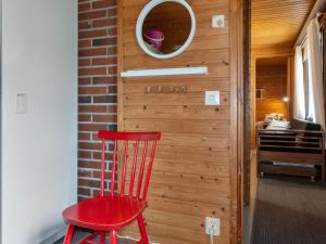 a red chair sitting next to a wall with a mirror at Holiday Home Mäkitupa by Interhome in Syöte