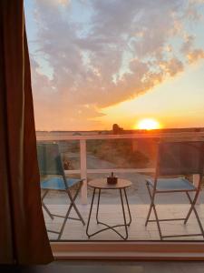 uma varanda com 2 cadeiras, uma mesa e um pôr-do-sol em Sunset View em Costinesti