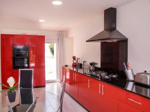 a kitchen with red cabinets and a black counter top at Holiday Home Baruffa by Interhome in Jávea