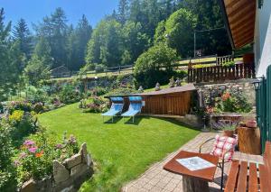 a backyard with a garden with benches and flowers at Dolomites Chalet CESA VEDLA -nature & silence in Ortisei
