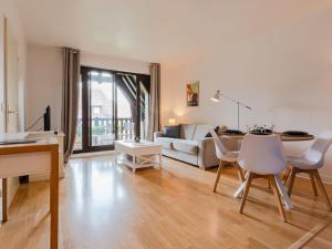 een woonkamer met een bank, een tafel en stoelen bij Apartment l'Hermitage-3 by Interhome in Deauville
