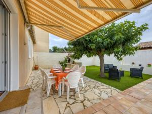 un patio con mesa, sillas y un árbol en Holiday Home La Voie Romaine by Interhome, en Sauvian