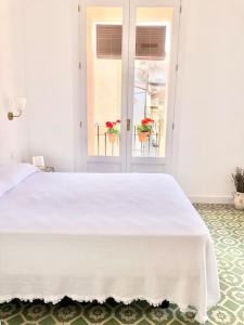 ein weißes Bett in einem Zimmer mit Fenster in der Unterkunft Tu alojamiento en Cáceres in Cáceres
