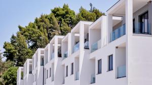 un bâtiment blanc avec des arbres en arrière-plan dans l'établissement Azar Luxury Suites, à Vlorë