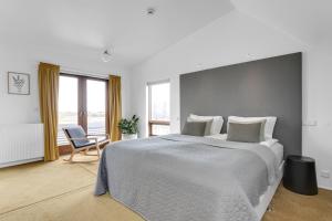 a white bedroom with a large bed and a chair at Eyvindarholt Guesthouse in Álftanes