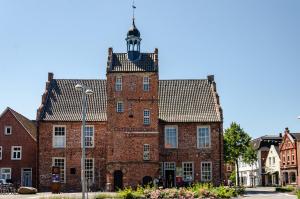 an old red brick building with a tower at Ferienhaus Sonnenschein - Wohnung 1 in Norden