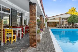 een patio met een tafel en stoelen naast een zwembad bij Stefania Hotel in Amarinthos