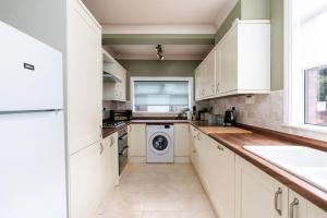 a kitchen with white cabinets and a washer and dryer at Free Parking Stylish House Near Humber Bridge in Barton-upon-Humber