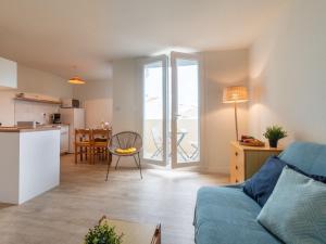 een woonkamer met een blauwe bank en een keuken bij Apartment Les Sables d'Or-12 by Interhome in Le Grau-du-Roi