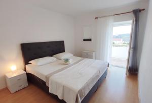 a bedroom with a large white bed with a window at Apartments Danica in Lopar